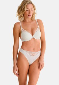 Witte bh en bijpassende slipset met kantdetail op de cups en de tailleband, gladde stof en een slanke silhouet.