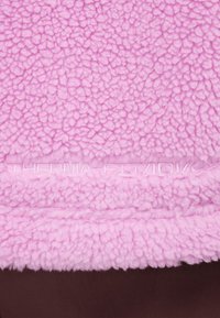 Rosa fleece-tyg med en texturerad yta, med en subtil "THERMA-FIT"-logotyp i präglad söm vid nederkanten.