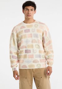 Lichtcrème sweatshirt met een patroon van meerkleurige vintage labels in roze, geel en lavendeltonen. Geribde manchetten en halslijn.