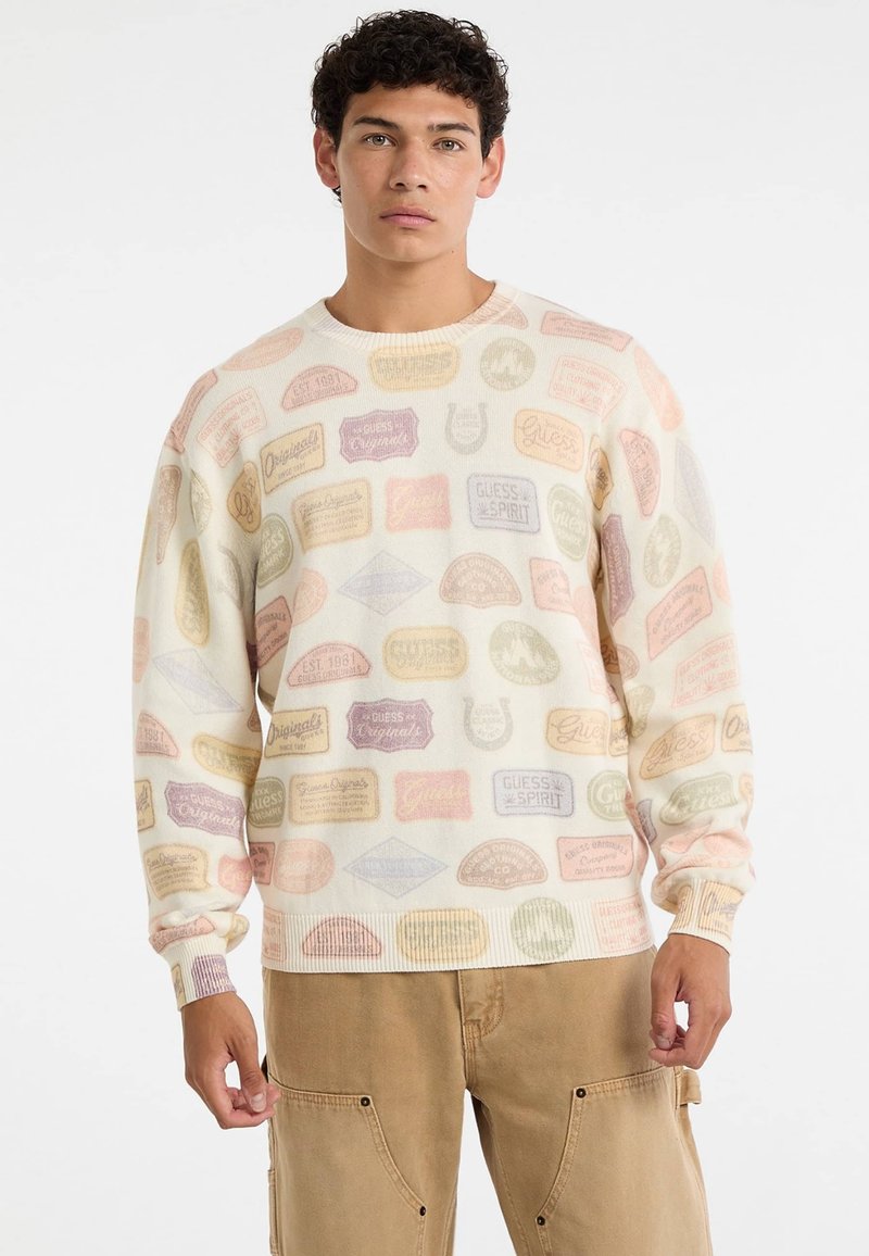 Lichtcrème sweatshirt met een patroon van meerkleurige vintage labels in roze, geel en lavendeltonen. Geribde manchetten en halslijn.
