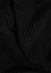 Tela negra con pliegues y pequeñas motas de purpurina dorada dispersas que crean un efecto estrellado sobre un material texturizado.