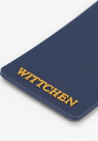Námořnická modrá kožená visačka s vyraženým zlatým nápisem "WITTCHEN." Hladký povrch, zaoblené rohy, minimalistický design.