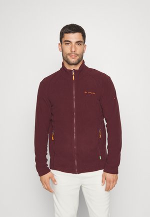 Burgunderfarbene Fleecejacke mit hohem Kragen, Frontreißverschluss und Seitentaschen mit orangefarbenen Reißverschlusszügen. Logo auf der linken Brust.