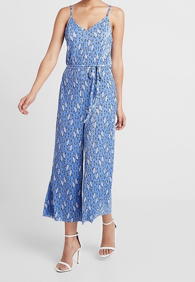 Modrý květinový overal s tenkými ramínky, výstřihem do V, nastavitelným páskem a širokými nohavicemi. Vyroben z lehké tkaniny, zdobený jemnými květinovými vzory.
