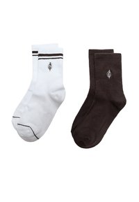 Due paia di calzini alla caviglia, uno bianco con strisce nere e logo, l'altro nero con logo bianco, esposti su uno sfondo bianco semplice.
