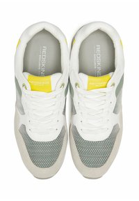 Chaussures de sport blanches et grises avec une tige en maillage texturé, des accents jaunes et une languette rembourrée avec un système de laçage.