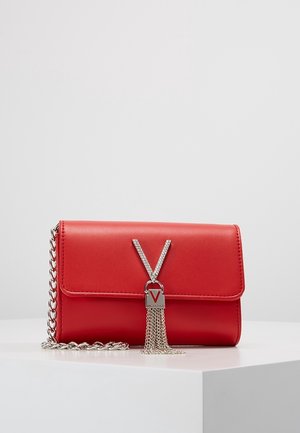 Clutch Valentino in pelle rossa con tracolla in catena argentata, logo 'V' decorato e tasselli argentati pendenti su superficie bianca.