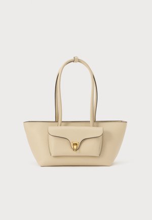 Beige leather handbag with two long handles, flat shape, a front flap pocket, gold hardware, and contrasting black trim along the edges.