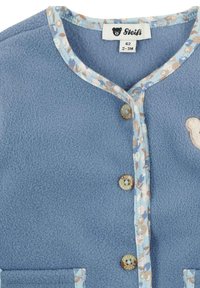 Light blue fleece jacket with a floral patterned trim, featuring two buttons and a bear emblem on the left side.