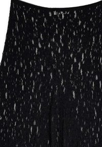 Tissu en dentelle noire avec un motif texturé, présentant une trame ouverte et des bords festonnés. Le design inclut une opacité variée et des détails complexes.