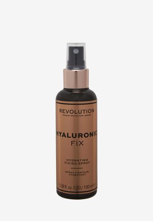 Bottiglia cilindrica nera con pompa metallica dorata. L'etichetta riporta "Hyaluronic Fix", dettagliando spray idratante e fissativo. Dimensione: 100 ml.