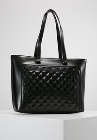 Black leather tote bag with a quilted front panel, smooth texture, two sturdy handles, and a zip closure. Features gold-tone hardware accents.