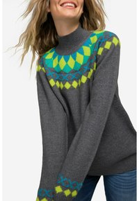 Grauer Strickpullover mit hohem Kragen, der ein leuchtendes geometrisches Muster in Grün und Blau an den Schultern und Bündchen aufweist.