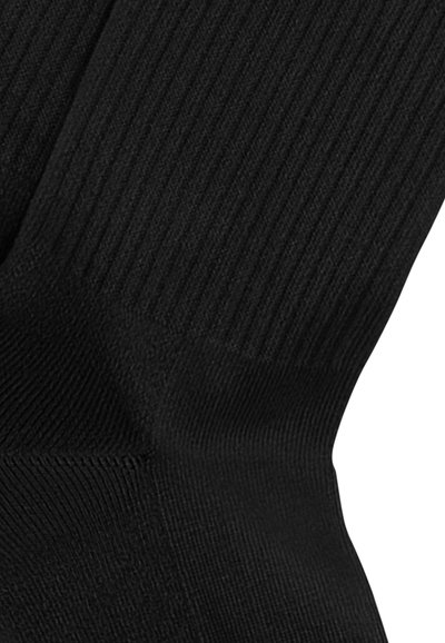 Calzino nero a coste con superficie testurizzata, dotato di una parte superiore liscia e tallone rinforzato. Il tessuto sembra morbido ed elastico.