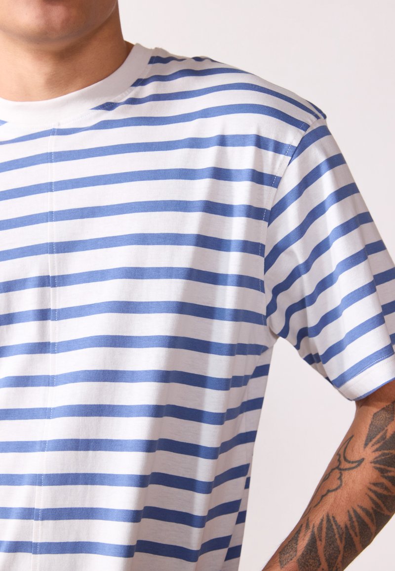Gestreiftes T-Shirt in Weiß und Hellblau, aus Baumwollmaterial, mit kurzen Ärmeln, rundem Ausschnitt und sichtbaren Nähdetails, leicht locker sitzend.