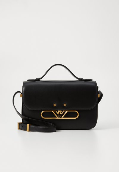 Sac à main en cuir noir au style structuré, avec des finitions en métal doré et un fermoir logo, poigné supérieure et bandoulière détachable.