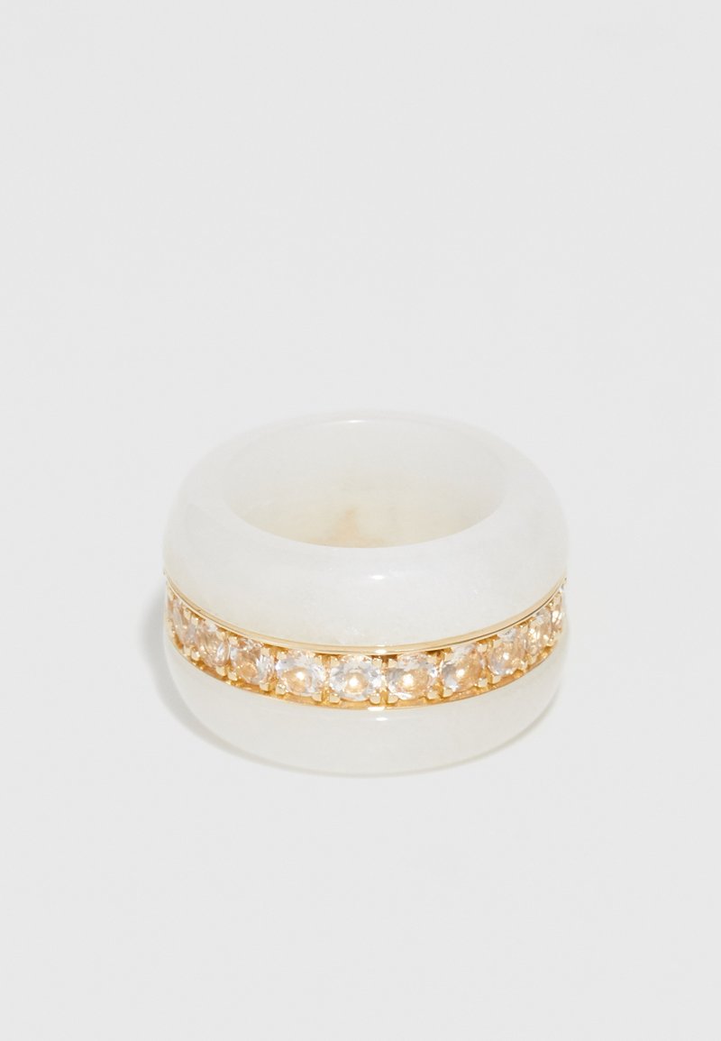 Prozirni bijeli prsten od smole sadrži zlatni pojas s prozirnim akcentima dragulja duž središta, glatku površinu i zaobljene rubove.
