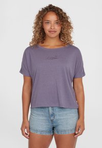Lilla t-shirt med korte ærmer og løs pasform, der har et diskret broderet logo i midten. Kombineret med lyseblå denimshorts.