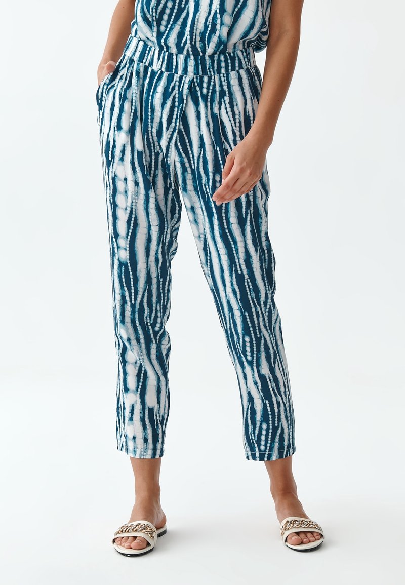 Pantalon ample à motif bleu et blanc avec une taille élastique et des poches latérales, présentant un design à rayures verticales.