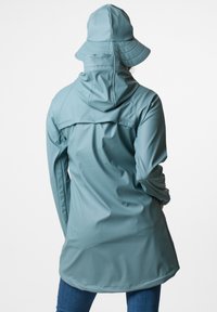 Vattentålig blå jacka med huva och ventilationsdetaljer på baksidan, tillsammans med en matchande bucket hat. Snygg design och mjuk textur.