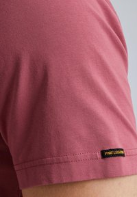 T-shirt a maniche corte e collo tondo in morbido tessuto rosa chiaro; presenta un'etichetta nera "PME Legend" sull'orlo; texture liscia e vestibilità regolare.
