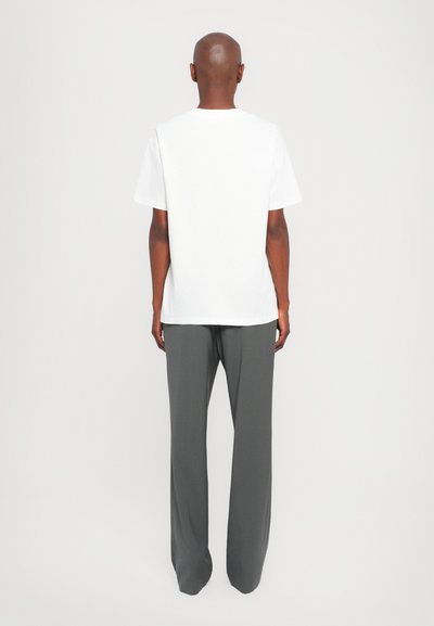 Weißes T-Shirt mit kurzen Ärmeln und graue weite Hose, minimalistisches Design, glatte Textur, gerade Passform, von hinten betrachtet.