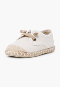 Chaussure en toile d'un blanc cassé avec un bout en beige et une semelle en jute tressé. Équipée d'un système de laçage et d'un design arrondi. Texture douce.
