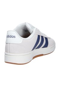 Sneaker bianca in suede con tre strisce blu navy, suola in gomma e colletto imbottito. Presenta il logo sul tallone e sulla linguetta.