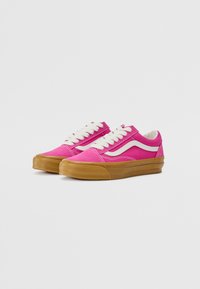Pink canvas sneakers with white accents, featuring round laces and a gum rubber sole. Low-top design with reinforced toe cap.