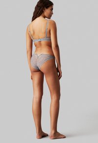 Light blue lace bra and thong set, featuring intricate wave patterns, adjustable straps, and a sheer, textured finish.