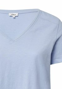 Lichtblauw T-shirt met korte mouwen en V-hals, gemaakt van zachte stof, met een subtiele textuur en gestikte details langs de kraag en schouders.