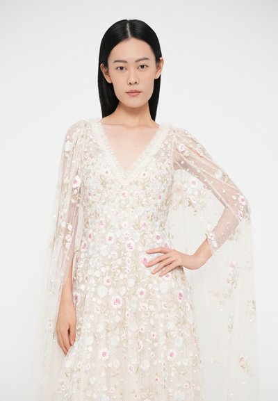 Vyšívané šaty s výstrihom do V, priesvitnými dlhými rukávmi a kvetinovými vzormi. Sú vyrobené z mäkkého, ľahkého materiálu s jemnými detailmi v pastelových farbách.