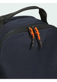 Marineblauwe stoffen rugzak met een gebogen vorm, voorzien van een zwarte rits en oranje trekkoorden. Gelaagde oppervlakte met een gevoerde schouderband.