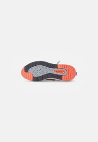 Semelle d'une basket avec une bande de roulement noire, grise et orange, affichant le logo Air Max dans la zone du médio-pied.