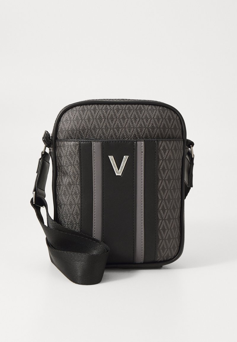 Black crossbody bag with a geometric pattern, silver logo accent, and contrasting textures. Adjustable strap for easy carrying.