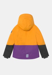 Hooded zimní bunda v oranžových, fialových a černých barevných blocích viděná zezadu s reflexní nálepkou poblíž lemu.