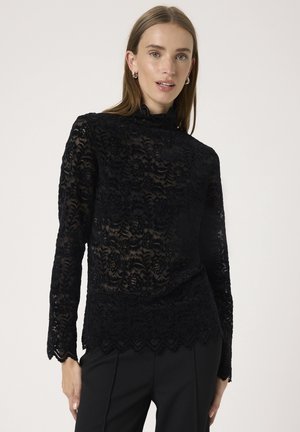 Schwarzes Spitzentop mit hohem Kragen und langen Ärmeln. Enthält florale Muster und einen gewellten Saum. Trägt man über maßgeschneiderten schwarzen Hosen.