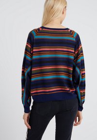 Striped oversized sweater in navy, featuring horizontal stripes of pink, orange, green, and blue. Soft texture with dropped shoulders.