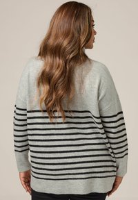 Pull oversized gris clair avec des rayures noires horizontales, texture douce, poignets et ourlet côtelés ; vue arrière montrant une coupe décontractée et un drapé.