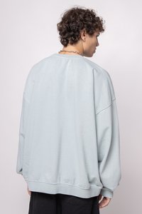 Hellblaues, übergroßes Sweatshirt mit Rundhalsausschnitt, überschnittenen Schultern und gerippten Bündchen. Glatte Textur mit lockerer Passform.