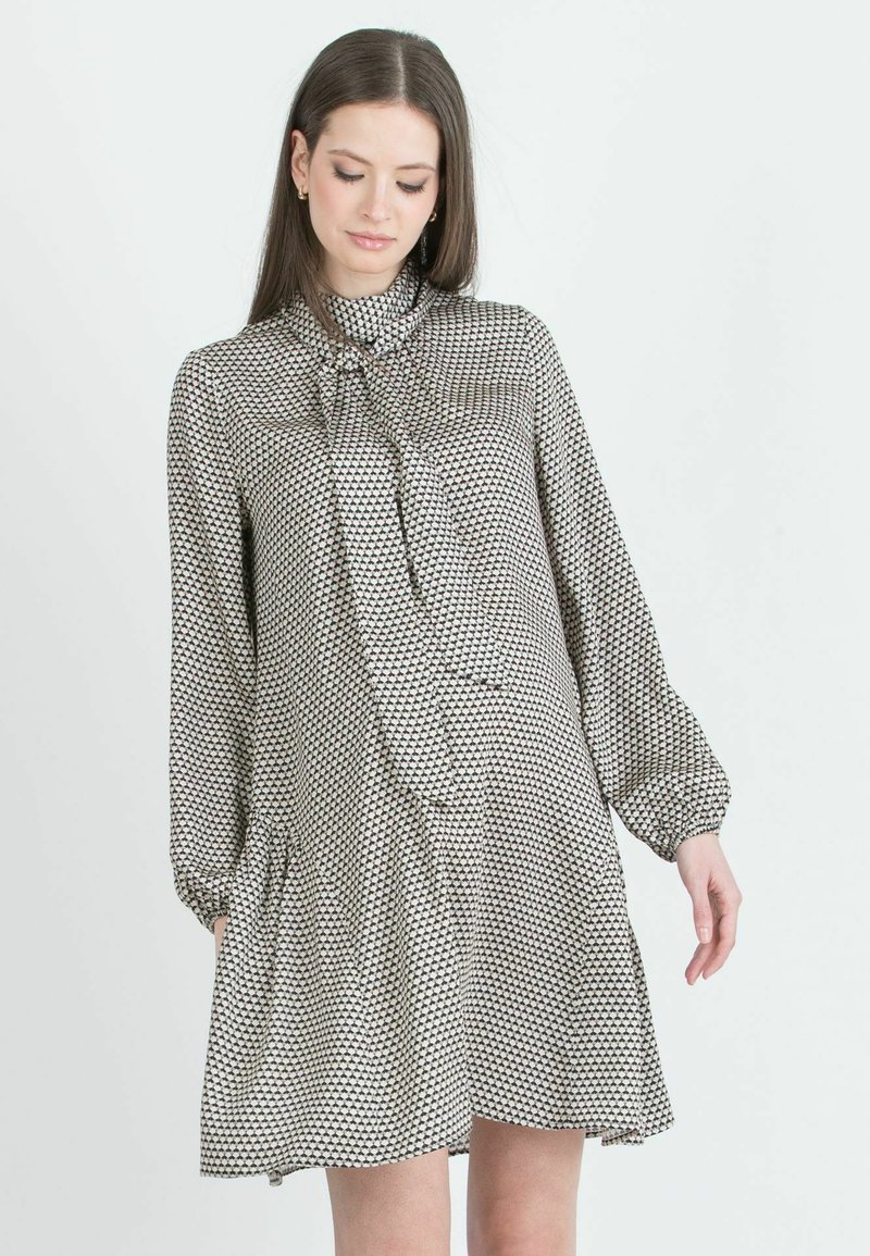 Černo-bíl dress s vzorem, vysokým výstřihem a mašlí, dlouhými rukávy a rozšířeným lemem; vyrobeno z lehkého materiálu.
