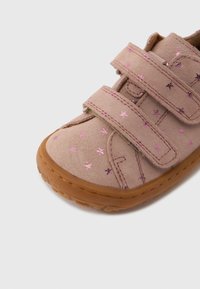 Chaussure en daim rose avec deux brides Velcro, ornée de petits motifs d'étoiles métalliques et d'une semelle en caoutchouc. Bout arrondi et détails cousus.