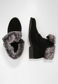 Bottines en daim noir avec bordure en fausse fourrure grise, dotées d'une semelle plate et d'un design à lacets. Remarquables par leur col texturé et leur silhouette élégante.