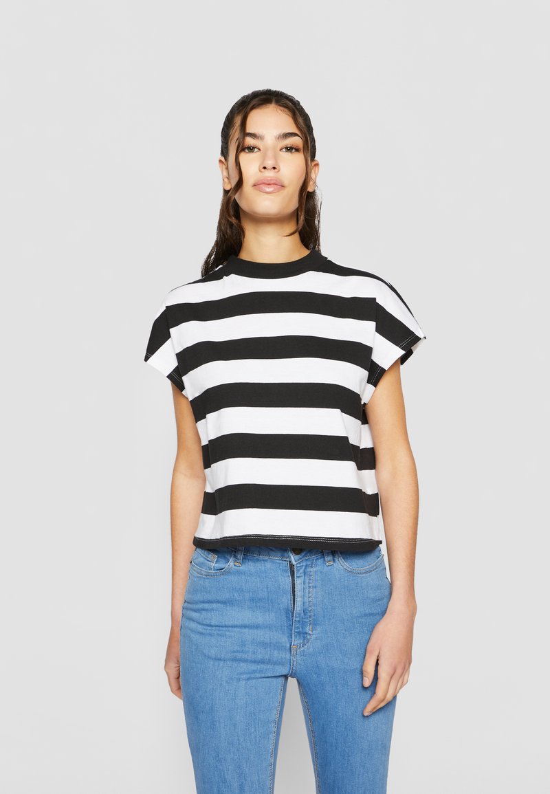 Zwart-wit gestreepte korte mouwen crop top met een ronde hals; gemaakt van zachte stof; gecombineerd met lichtblauwe jeans.