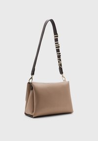 Beige läderhandväska med en strukturerad form, med ett svart rem med gulddetaljer och en texturerad yta.