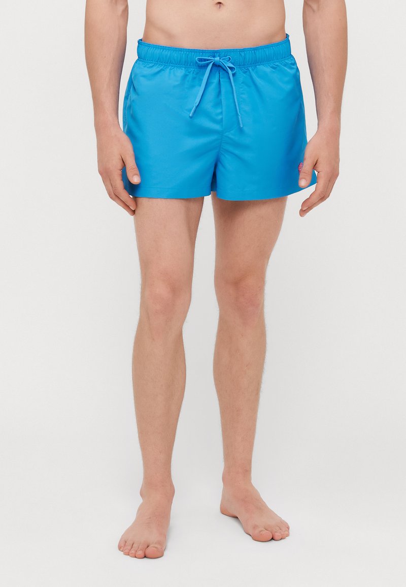 Shorts de bain bleus avec une taille élastique et un cordon de serrage ajustable. Fabriqués en matériau léger, ils ont une texture douce et une coupe décontractée.