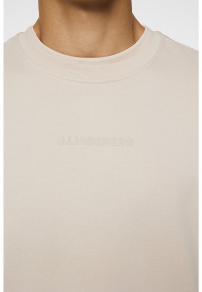 Beige bomulds sweatshirt med rund hals og ribbet struktur. Har diskret prægning af brandet på brystet. Struktureret pasform, standardkrave.