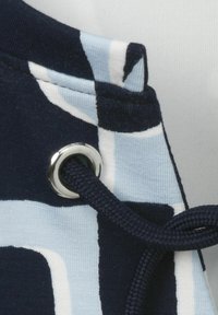 Stoff in Marineblau und Hellblau mit Ösen und marineblauen Kordel-Details. Verfügt über eine glatte Textur und ein geometrisches Design.