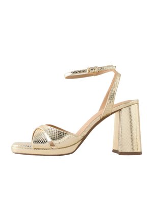 Gold metallic high-heeled sandal with ankle strap, block heel, and crisscross open toe design in a textured snake pattern.