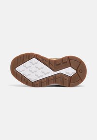 Suela de zapato con un diseño de goma texturizada de base blanca y una suela marrón. Los patrones incluyen agarres hexagonales y triangulares para mayor tracción.